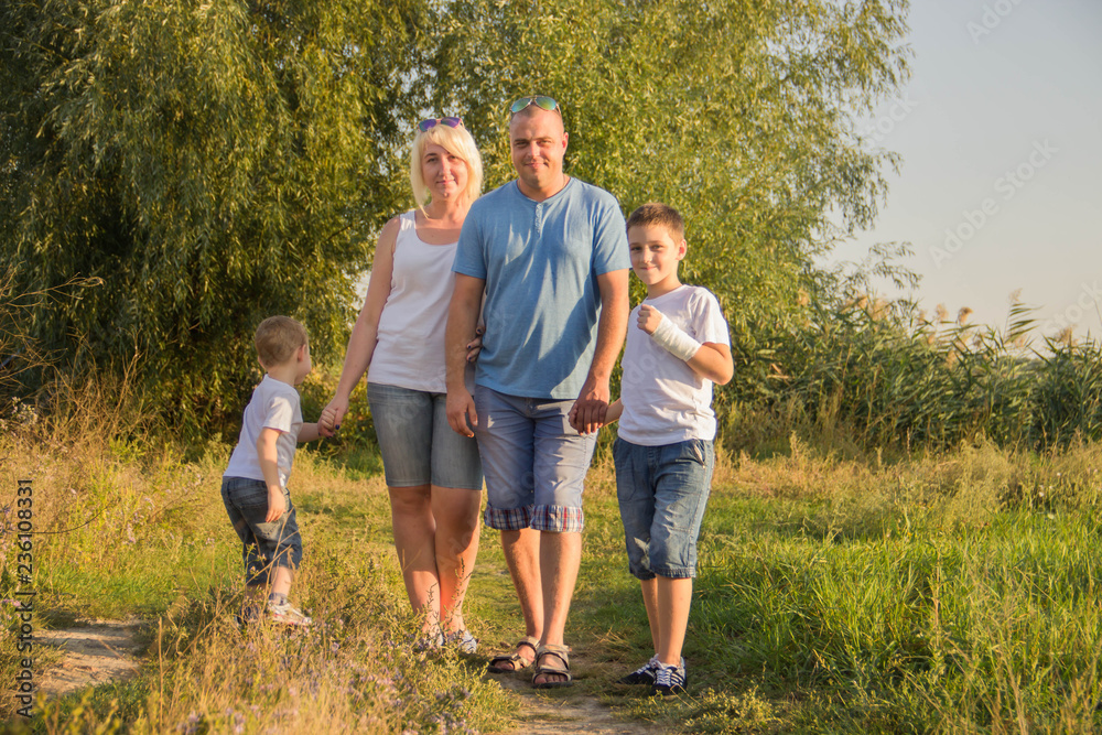 Fototapeta premium Happy parents of two boys relaxing in nature
