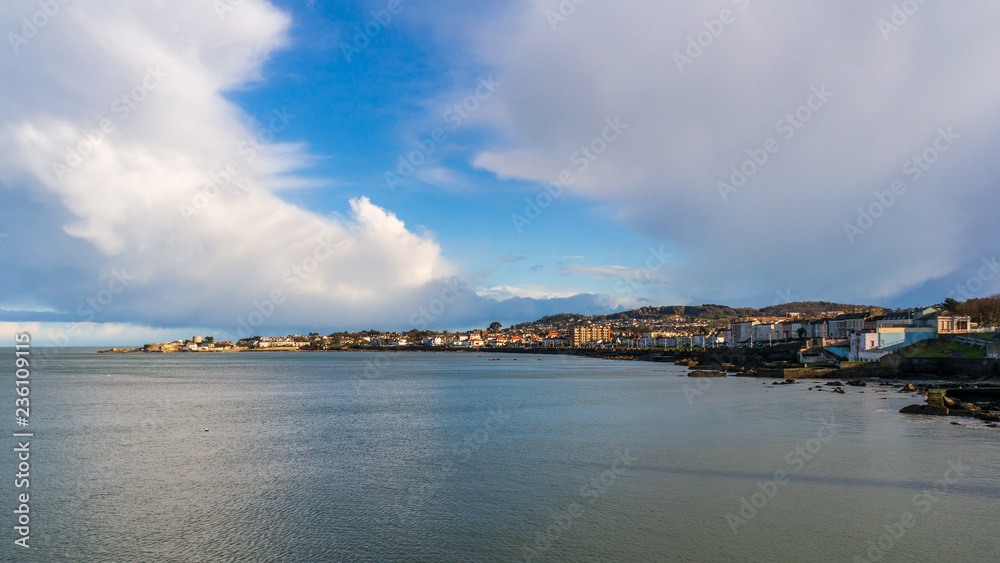 Landscape of Dun Laoghaire village located on the Irish East Coast, County Dublin, Ireland, well known tourist destination. Dramatic clouds over a coastal town.