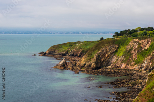 Irish coast landscape with rugged cliffs covered in green grass on a cloudy summer day. Howth Cliff Walk  County Dublin  Ireland.