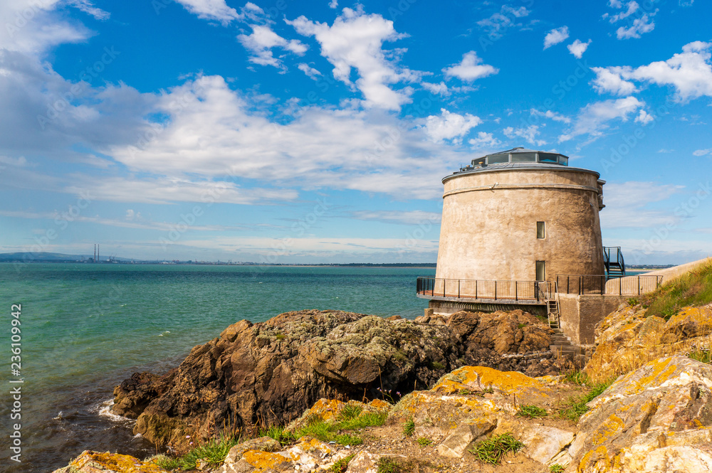 Ireland landscape. Martello Tower under a beautiful blue sky with white clouds on the coast of Sutton in County Dublin. Ireland landscape. Martello Tower under a beautiful blue sky with white clouds on the coast of Sutton in County Dublin.