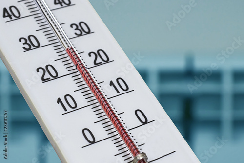 White alcohol room thermometer shows a comfortable temperature in the house against the background of a heating radiator. photo