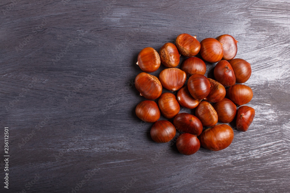 pile of sweet chestnuts on black wooden background pile of sweet chestnuts on black wooden background