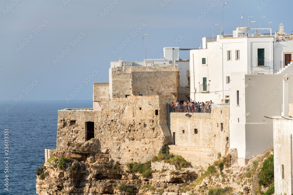 POLIGNANO A MARE, ITALY - JULY 6 2018: Tourist looking from view in historic center to lovely beach Lama Monachile, Adriatic Sea, Apulia, Bari province on July 6, 2018 in Polignano a Mare, Italy.