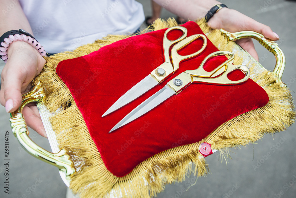 Golden scissors on red pillow in woman hands