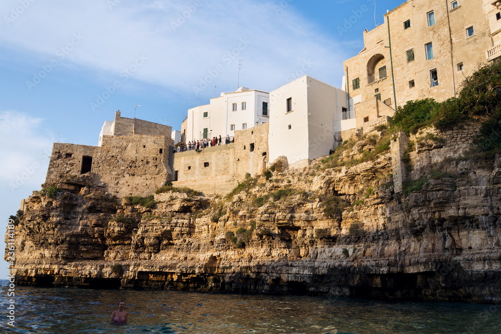 POLIGNANO A MARE, ITALY - JULY 6 2018: Tourist looking from view in historic center to lovely beach Lama Monachile, Adriatic Sea, Apulia, Bari province on July 6, 2018 in Polignano a Mare, Italy.