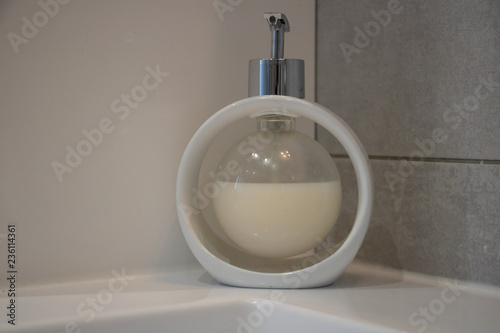 Distributeur de savon liquide en forme de bulle, blanc sur un rebord de lavabo salle de bains très moderne blanc épuré photo