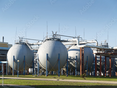 Industrial landscape with view of several ball gasholders with lightning protection and safety valve on modern chemical production.