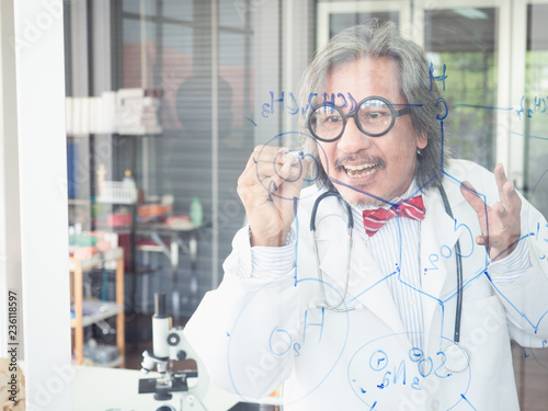 asian scientist writes a formula on a glass Board