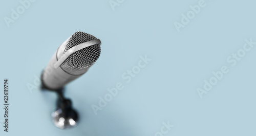 technology and audio equipment concept - close up of microphone at recording studio or radio station on blue background