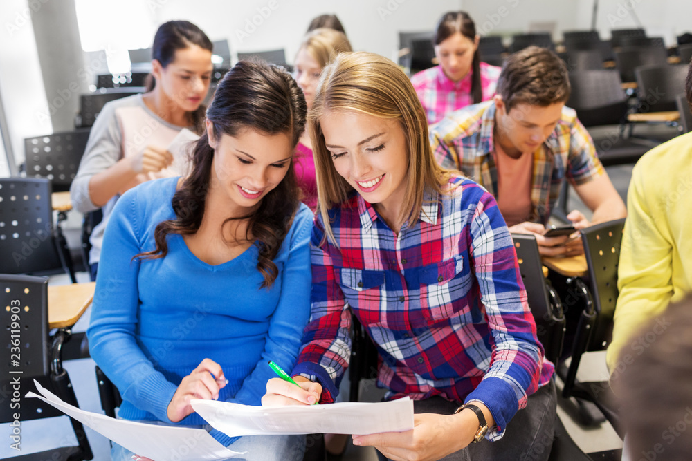 Obraz premium education, high school and people concept - happy student girls with tests at lecture hall