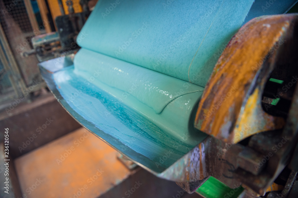 An empty quiet industrial wallpaper and paint factory with giant industrial wall paper rolling machines in various colours. blue paint being mixed. An empty quiet industrial wallpaper and paint factory with giant industrial wall paper rolling machines in various colours. blue paint being mixed.