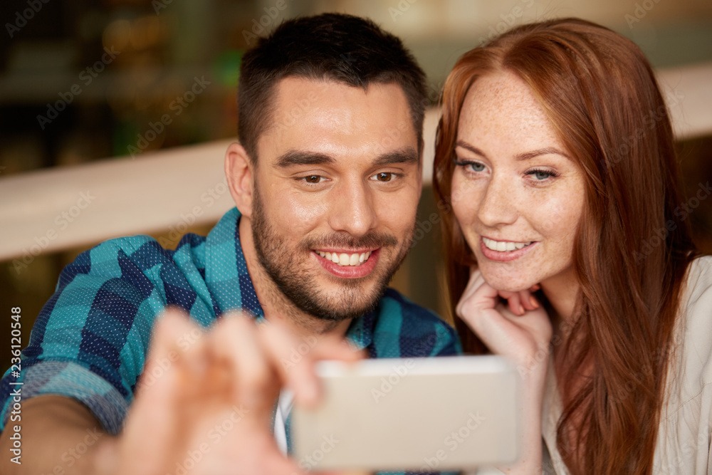 leisure, technology and people concept - happy couple taking selfie by smartphone at restaurant
