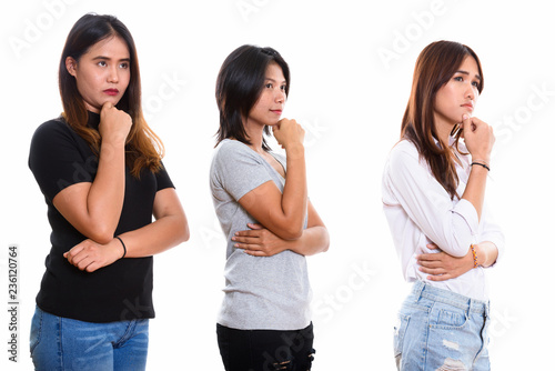 Studio shot of three young Asian woman friends thinking while lo