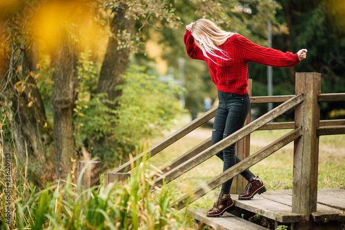beautiful happy girl in a red sweater outdoors, woman is resting at sunset