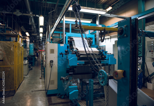 An empty quiet industrial wallpaper and paint factory with giant industrial paint rolling machines, printing white wallpaper.