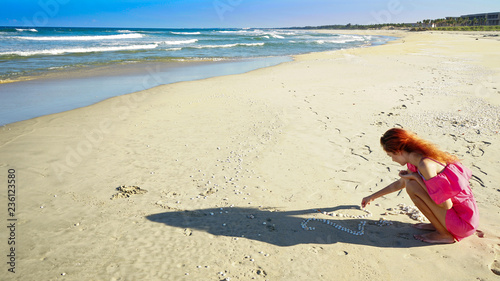 Girl with New year deer horns drinking coconut with 2019 drawing on the beach