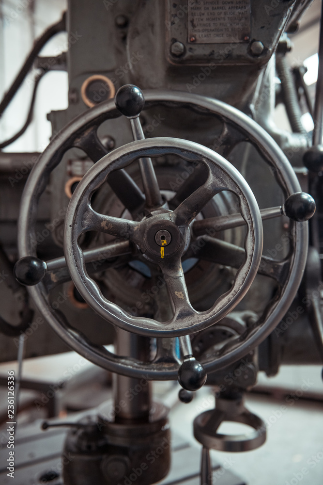 Obraz premium Beautiful matte silver metal industrial machinery steel cog handles in a rustic industrial factory setting. Well used processing machinery parts.