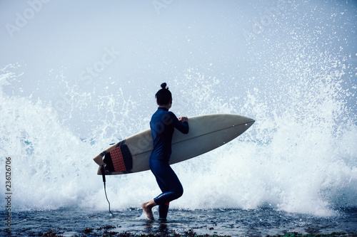 Photography Woman surfer with surfboard going to surf the big waves
