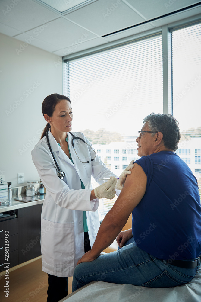 Obraz premium Doctor giving male patient a shot in the arm