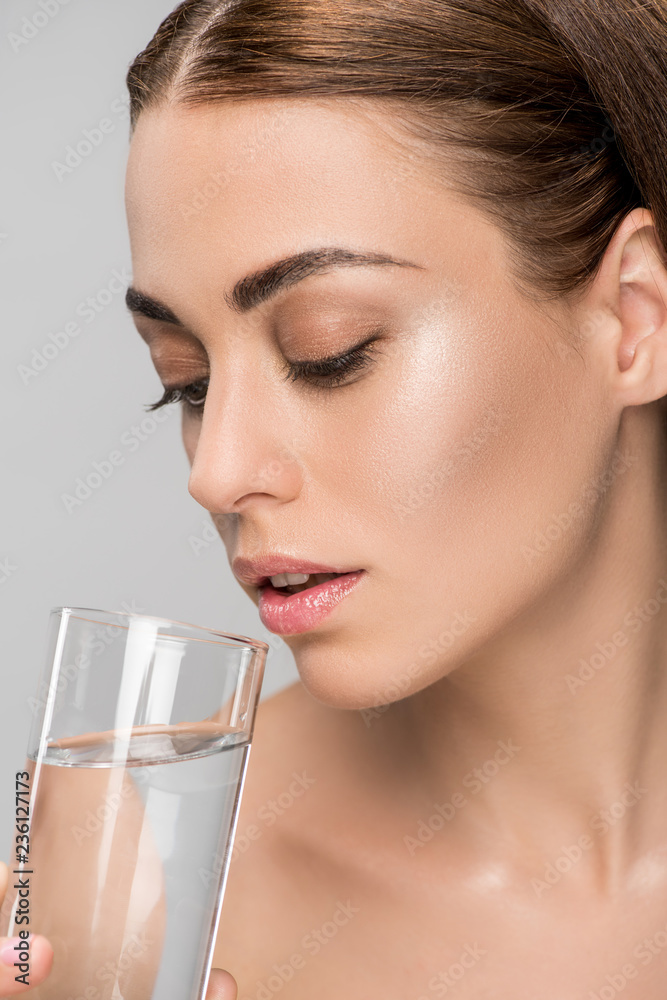 attractive young woman drinking water isolated on grey attractive young woman drinking water isolated on grey