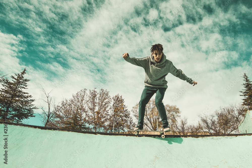 Guy skateboarder riding a skateboard on a skatepark. Young man jumping with a skateboard Guy skateboarder riding a skateboard on a skatepark. Young man jumping with a skateboard