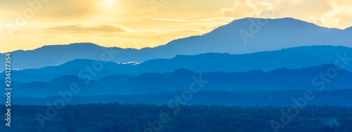 Landscape scene of colorfull sunset sky with mountain range and forest. © torjrtrx