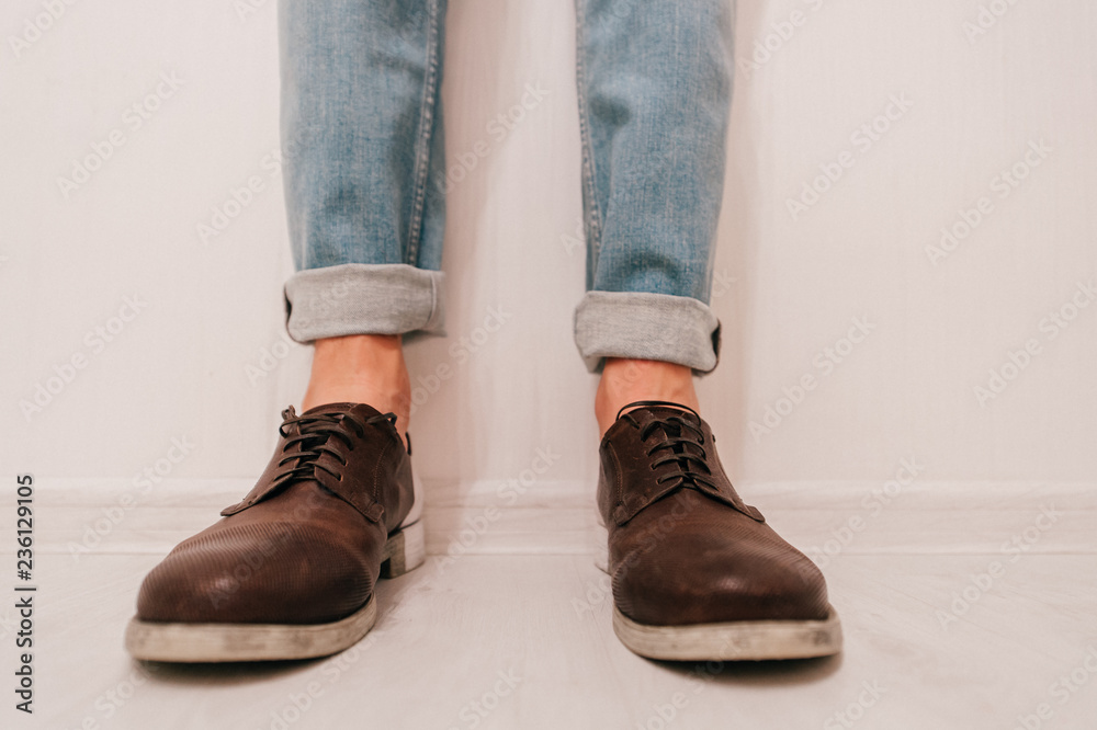Part of men's legs in rolled up jeans and boots isolated on light background Part of men's legs in rolled up jeans and boots isolated on light background