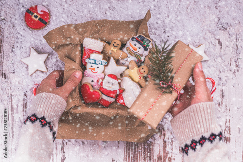 Female hands holding a Christmas gift box and gingerbread cookies