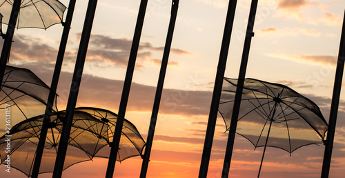 atmospheric shot of umbrella installation exterior design object in waterfront sea shore line city district in evening romantic sunset sky wallpaper background