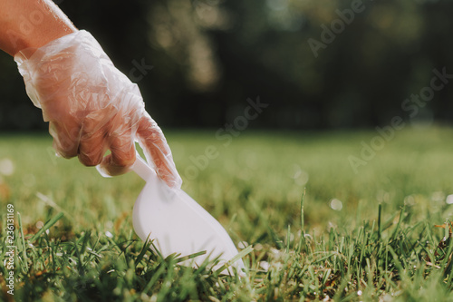 Canvas Print Close up of gloved hand holding scoop and cleaning up after dog on grass