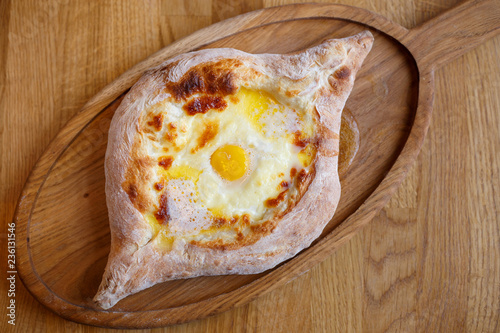 Adjarian open khachapuri with egg on wooden board photo