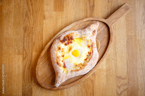 Adjarian open khachapuri with egg on wooden board photo