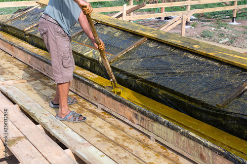 Worker at a construction site at home covers antiseptic boards. Impregnation of boards.