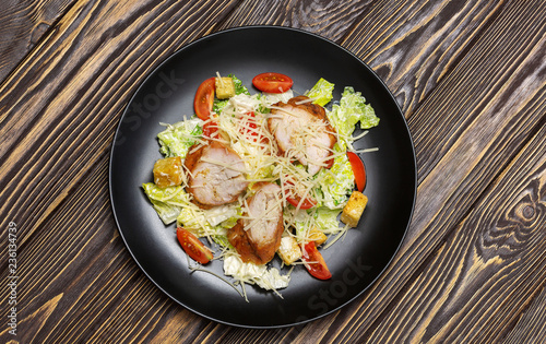 Salad in a plate on wooden background, top view