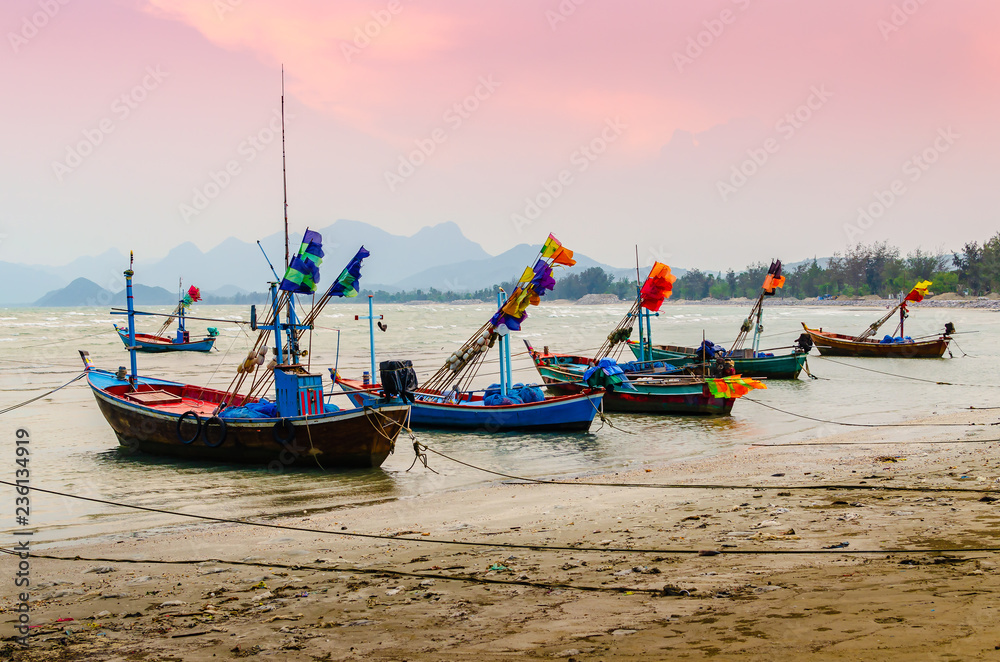 Fototapeta premium Small fishing boats anchor at beach in cloudy sunset sky.