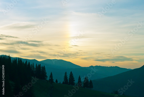 Dramatic sunrise in the mountains with little rainbow