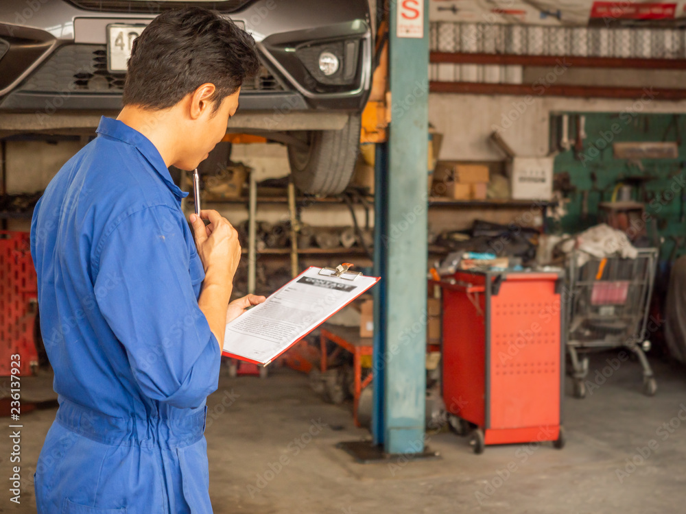 handsome asia man automotive mechanc in garage with copy space