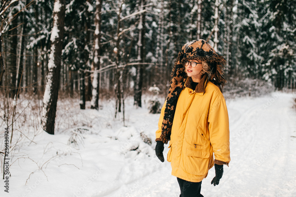 young girl in yellow coat in snowy forest