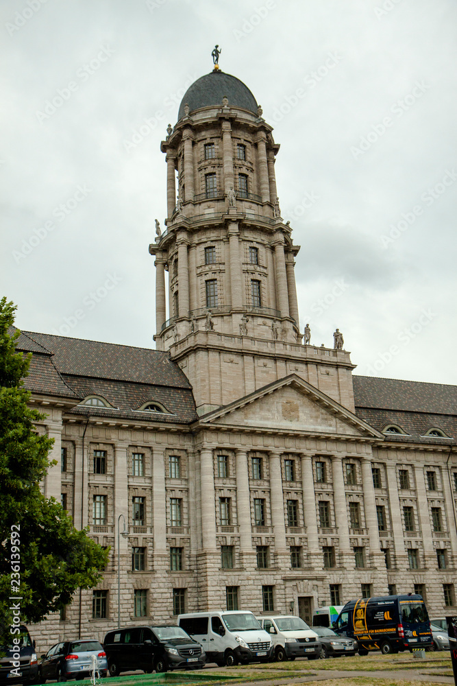 Berlin Old Town Hall. The majestic old building with tower and statues. Gray building on a cloudy sky background. German flags. City landscape.