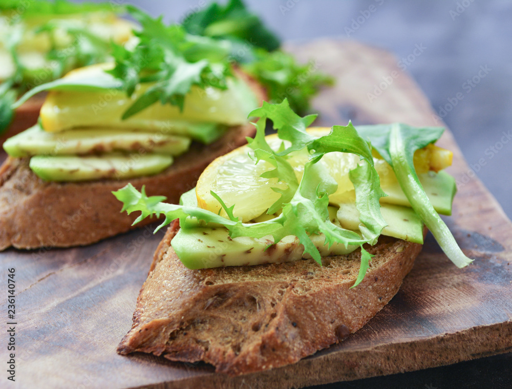Sliced avocado with lemon on toast bread with green salads on top. Buckwheat bread, vegetable and fruit. Avocado and lemon slices is perfect gourmet combination. Sliced avocado with lemon on toast bread with green salads on top. Buckwheat bread, vegetable and fruit. Avocado and lemon slices is perfect gourmet combination.