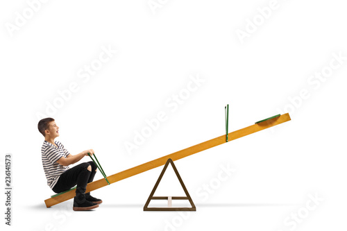 Smiling boy sitting alone on a seesaw photo