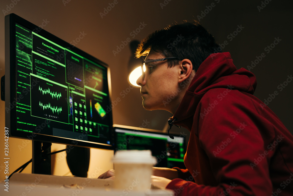 hacking the system. teenager working on computer late night at his apartment hacking the system. teenager working on computer late night at his apartment