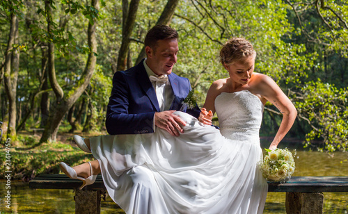 A romantic couple sitting on a bench in nature, wedding day, flowers, love