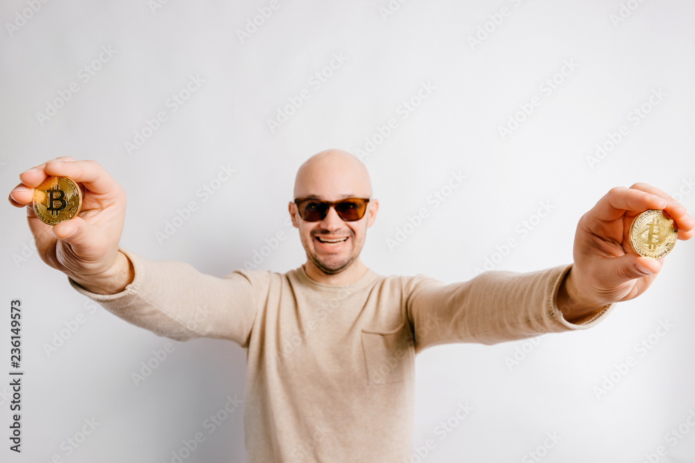Bald man in dark glasses stretches forward two coins bitcoin Bald man in dark glasses stretches forward two coins bitcoin