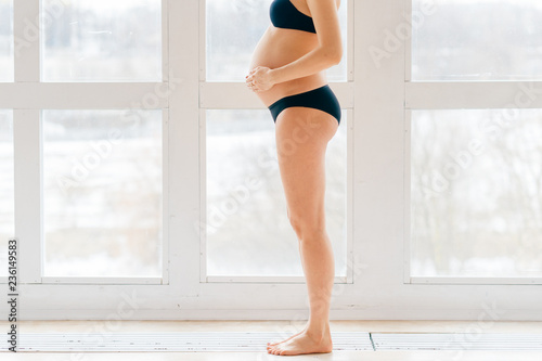 part Pregnant girl in lingerie stands sideways and put her hands on her belly