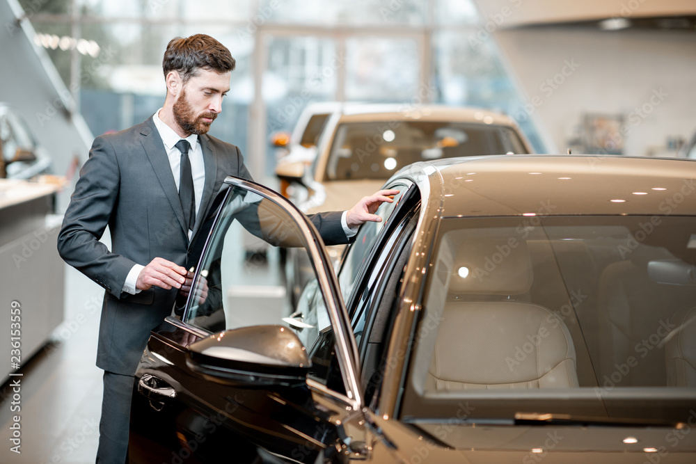 Elegant businessman choosing new luxury car looking at the car intreior in the showroom