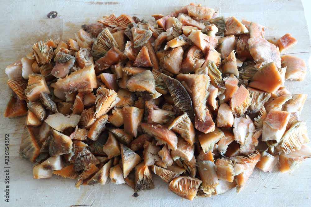 Minced saffron milk cap mushrooms (Lactarius deliciosus) caps, similar to Lactarius Sanguifluus and Lactarius Deterrimus, on a wooden cutting board