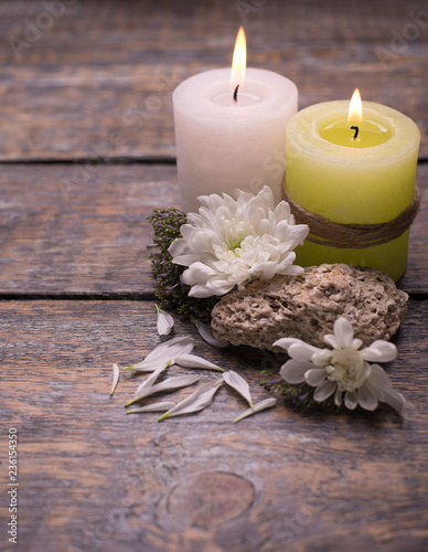 Two aromatic candles with flowers on a wooden background with copy space.