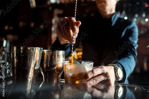 Expert Bartender is making cocktail at bar. photo