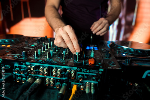 Dj mixes the track in the nightclub at party. In the background laser light show